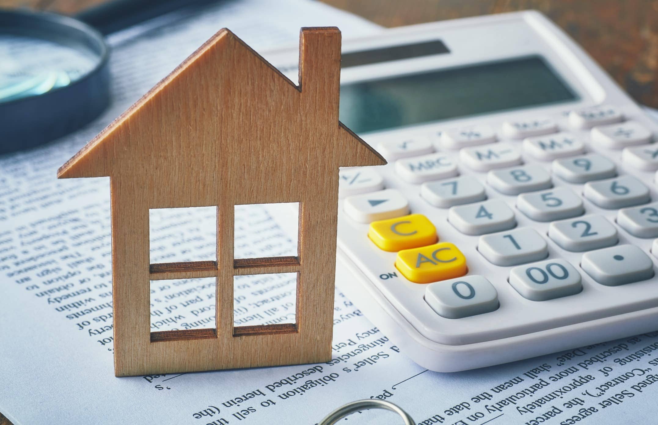 Ein Haus und ein Taschenrechner, verdeutlichen die Dringlichkeit einer detaillierten Kostenübersicht bei derzeitiger Immobilienpreise| Immobilienmakler Essen Monica Kirchner